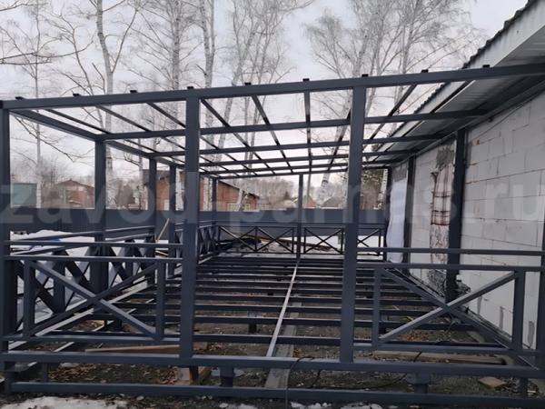 Длинная металлическая терраса с односкатной крышей и X-образными перилами
